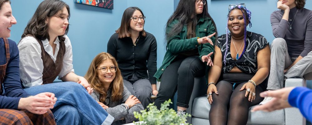 Students and faculty have a casual conversation in a meeting room.